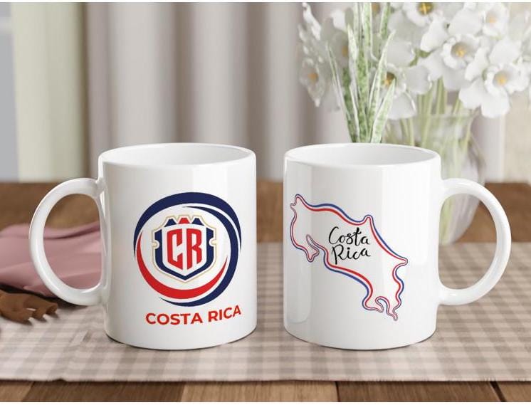 Two white mugs with Costa Rica-themed designs on a table with a checkered tablecloth.