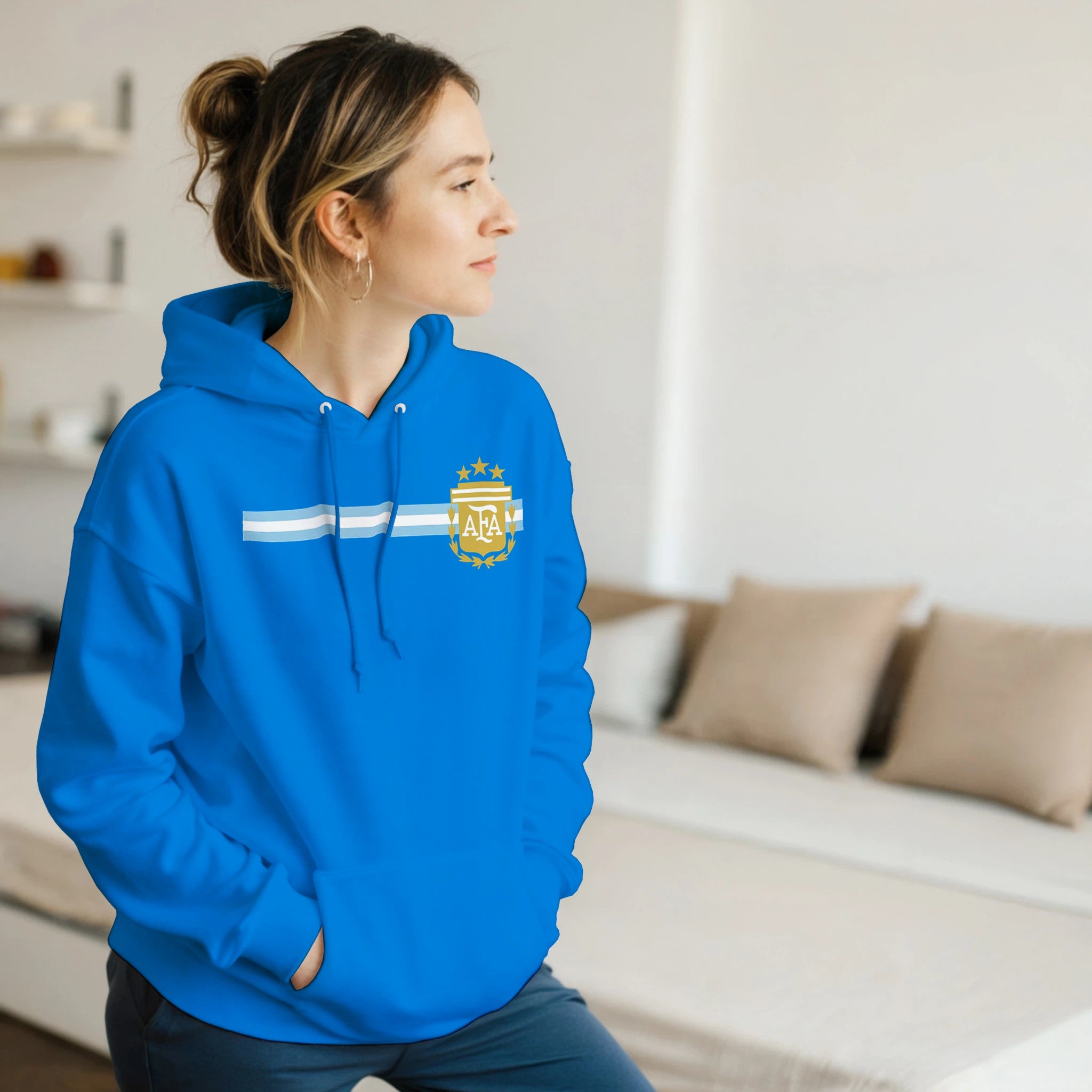 Person wearing a blue hoodie with a logo in a living room