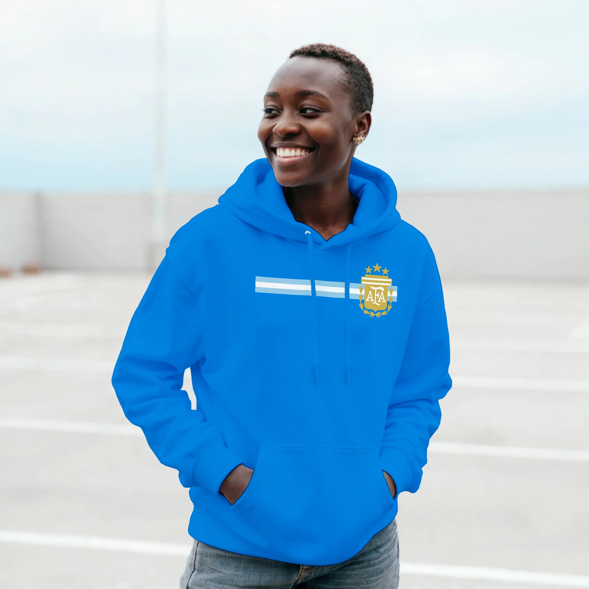Person wearing a blue hoodie with a logo, standing outdoors.