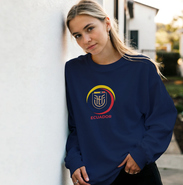 Woman wearing a navy blue sweatshirt with a logo and text, standing against a light-colored wall.