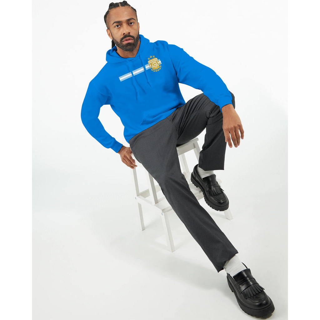 Man wearing a blue hoodie and gray pants sitting on a white stool against a white background