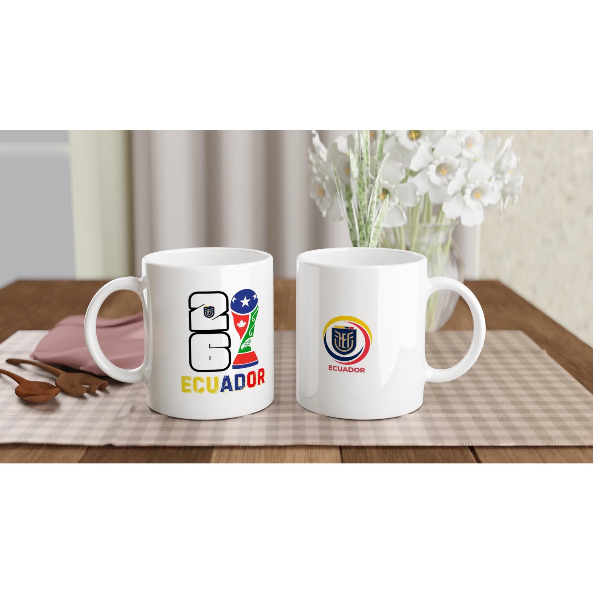 Two white mugs with Ecuadorian designs on a table with a checkered tablecloth.