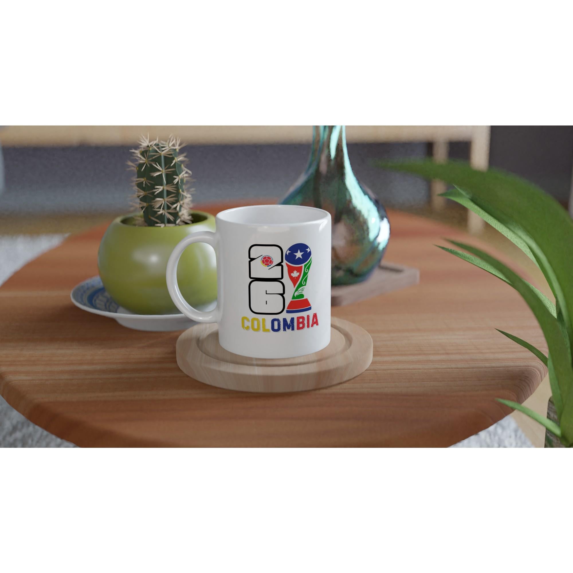 White mug with 'Colombia' text and logo on a wooden table with plants